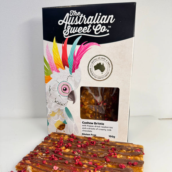 Cashew Brittle with decorative elements and packaging from The Australian Sweet Co on a white background