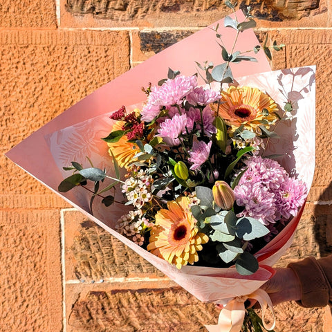 Bouquet of flowers held against a stone wall