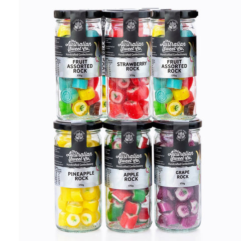 Assorted fruit rock candies in clear jars with black lids on a white background